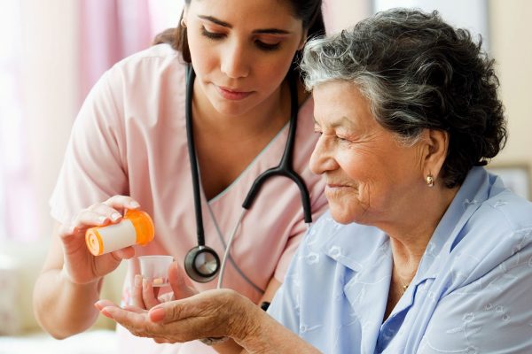 B16CP0 Hispanic nurse helping senior woman with medication--royalty free--nurse--paitent--at home health care--pills